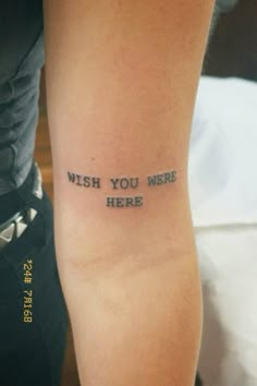 a person with a tattoo on their arm that says wish you were here and the words are in cursive font