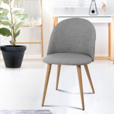 a grey chair sitting in front of a potted plant on top of a white floor