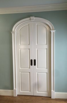 an empty room with two white doors and a cat on the floor next to it