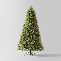 a white christmas tree with lights on it's top and base, in front of a gray background