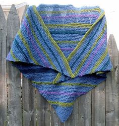 a crocheted shawl draped over a wooden fence