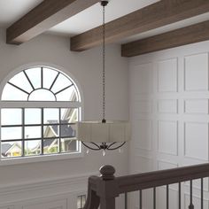 a chandelier hanging from the ceiling in a room with white walls and wood beams