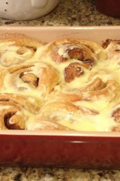 a red casserole dish filled with cinnamon rolls