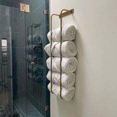 towels are stacked on a towel rack next to a glass shower door in a bathroom