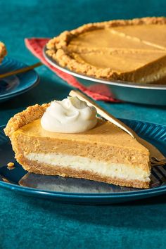 a slice of pumpkin pie on a blue plate with a fork and two plates behind it