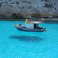 a small boat floating in the blue water