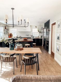 an open kitchen and dining room with wood flooring, black cabinets and white walls