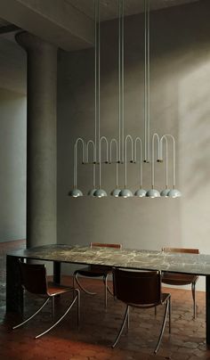 a dining room table with chairs and lights hanging from the ceiling