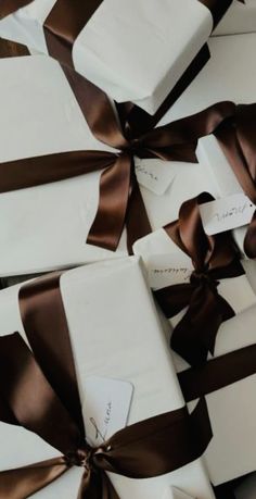 many white boxes with brown ribbons and tags on them are wrapped in chocolate satines