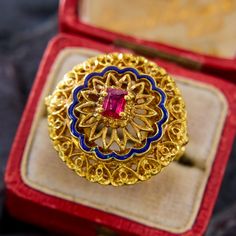 This highly detailed ring from Italy has ornate pierced goldwork accented by an undulating blue enamel border, and centered with a rectangular step cut ruby. The rich color of the gold has a very luxurious feeling. The ring is crafted in 14k yellow gold and is currently a size 6. Please note that the ruby has natural surface-reaching inclusions and that there is a slight nick in the blue enamel, neither of which affects wearability. Ceremonial Gold Ruby Ring With Intricate Design, Gold Ruby Ring With Intricate Design For Ceremonial Occasions, Ornate Gold Ruby Ring, Ceremonial Yellow Gold Ruby Ring With Intricate Design, Elegant Yellow Gold Meenakari Rings, Intricately Designed Yellow Gold Ruby Ring As Gift, Gold Luxury Ceremonial Enamel Ring, Ornate Gold Ring With Ruby, Luxury Gold Enamel Ring For Ceremonial Occasions