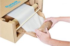 a person holding a roll of paper in a cardboard box