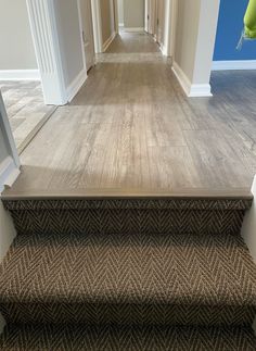 an empty hallway with carpeted stairs leading to another room