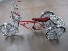 a red tricycle with chrome rims and wheels