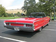 an old red car parked in a parking lot