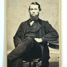 an old black and white photo of a man with a beard sitting in a chair