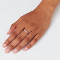 a woman's hand with a diamond ring on her left hand and pink sapphire in the middle