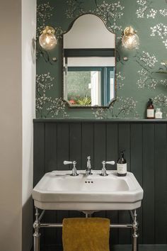 a bathroom sink sitting under a mirror next to a wall mounted faucet with lights on it