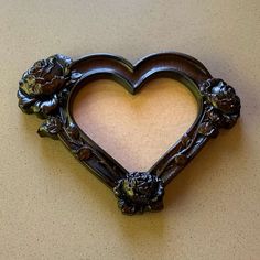 a heart shaped frame with flowers and leaves on the bottom is hanging on a wall