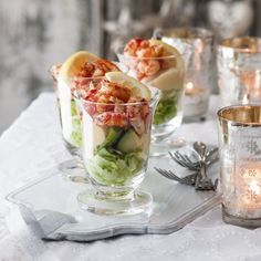 three glasses filled with food sitting on top of a white table covered in silverware