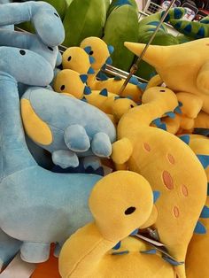 several stuffed animals are on display at a toy store, including two blue and one yellow dinosaur