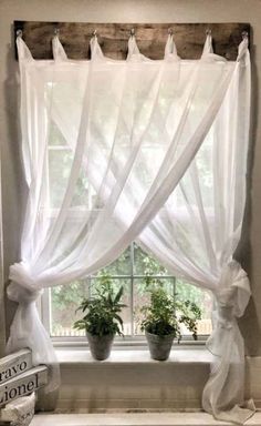 a window with curtains and potted plants in it