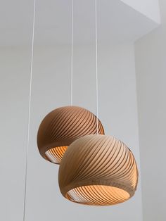 three circular wooden lights hanging from strings in a room with white walls and flooring