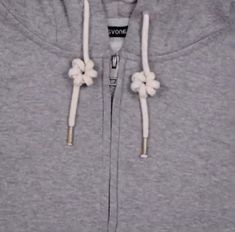 a grey hoodie with white flowers on the front and side zippers that are attached to it