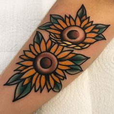 a sunflower tattoo on the arm with leaves and petals around it's center