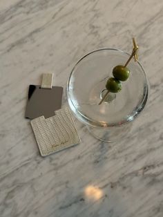 two olives in a glass on a marble table