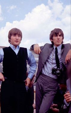 two men standing next to each other wearing ties and vests, one with his arm around the other's shoulder