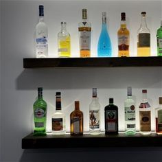 several bottles of alcohol are lined up on a shelf in front of a wall mounted light