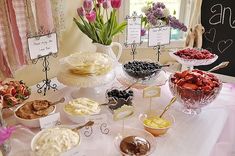 a table topped with lots of desserts next to a window