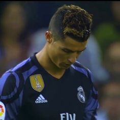 a soccer player with dreadlocks on his head looking down at the ball in front of him