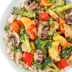 a white bowl filled with stir fry vegetables on top of rice and broccoli