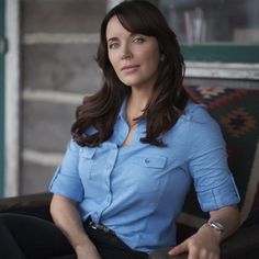 a woman sitting in a chair wearing a blue shirt