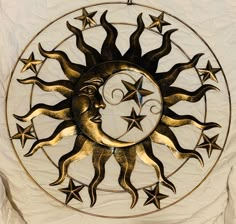 a metal sun and moon decoration hanging on a white sheet with stars in the background