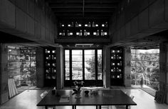 an empty dining room with large windows and wooden table in front of the door to another room