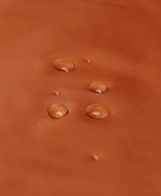 three drops of water sitting on top of an orange cloth with white dots in the middle