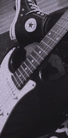 a black and white photo of someone's foot with an electric guitar on the ground