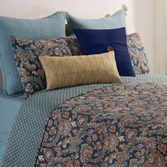 a bed covered in blue and brown pillows