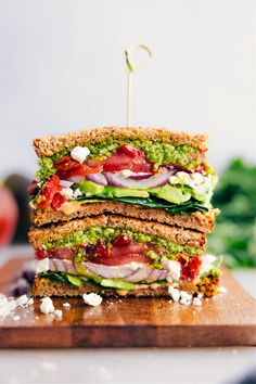 a stack of four sandwiches sitting on top of a wooden cutting board