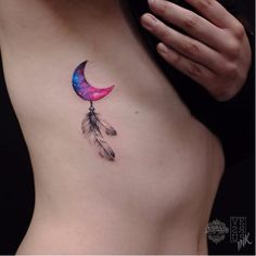 a woman's stomach with a colorful moon and feather tattoo on it