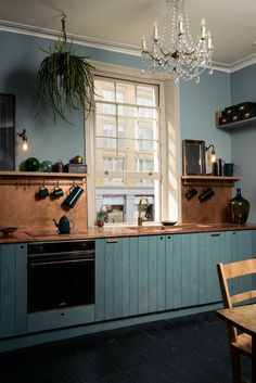 a kitchen with blue cabinets and a chandelier