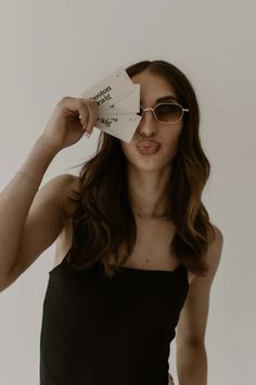 a woman wearing sunglasses holding up two tickets