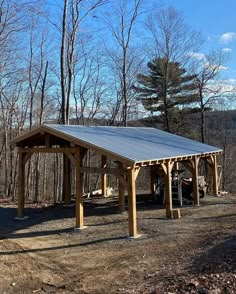 a wooden structure with a metal roof in the woods