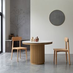 a dining table with two chairs and a vase on the table in front of it