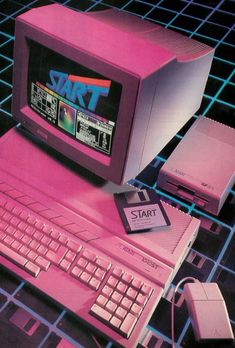 an old computer with a pink keyboard and mouse on top of it, surrounded by other electronic gadgets