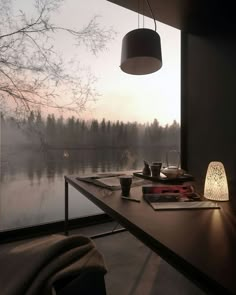 a desk with a lamp on it next to a window overlooking a body of water