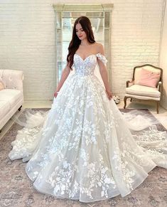 a woman in a white wedding dress standing on a carpeted floor with her hands behind her back