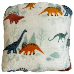 a pillow with dinosaurs and trees on it